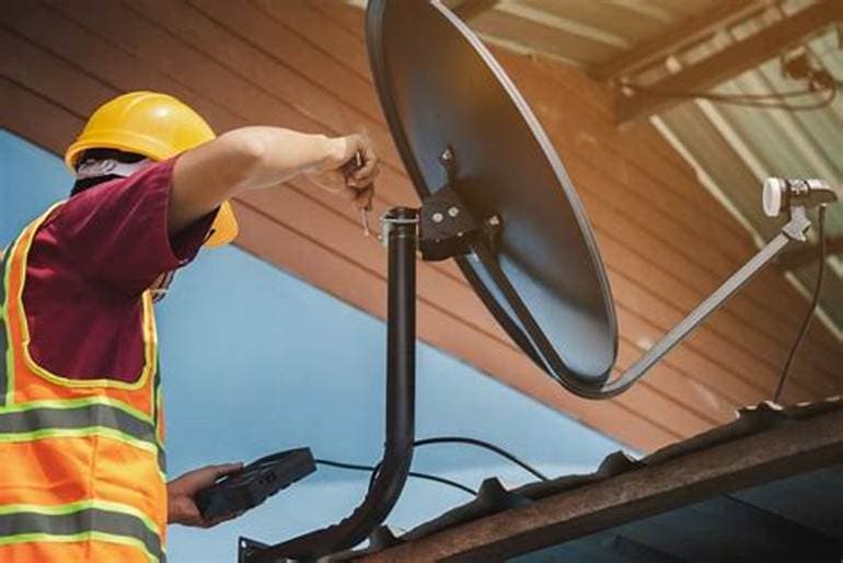 A Micgrand technician installing a satellite dish
